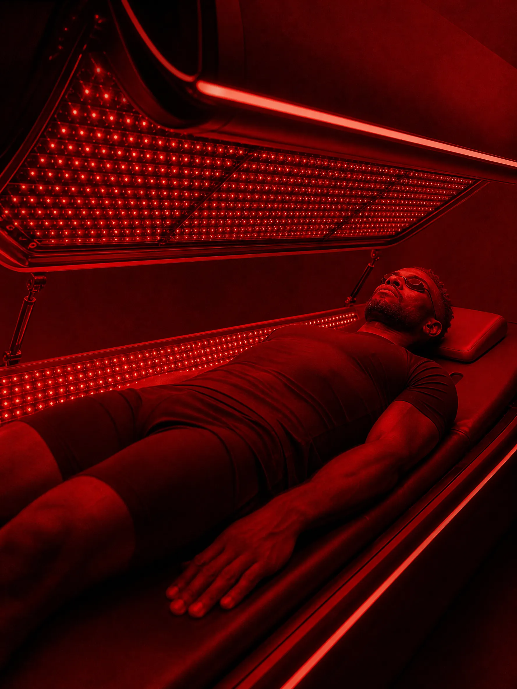 Guest bathed in red light inside a red light therapy bed